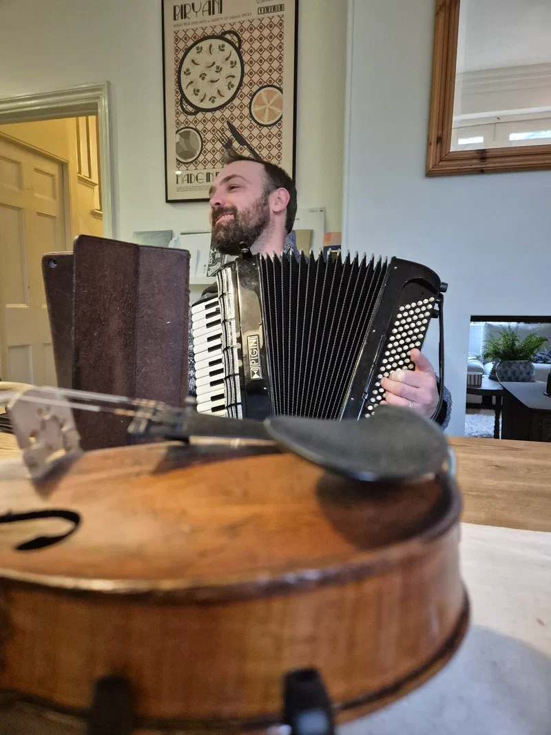 Dom playing the accordion at a daytime event