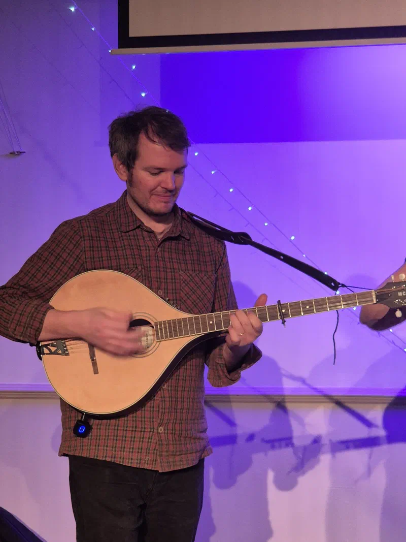 Tom playing the bouzouki under purple stage lighting
