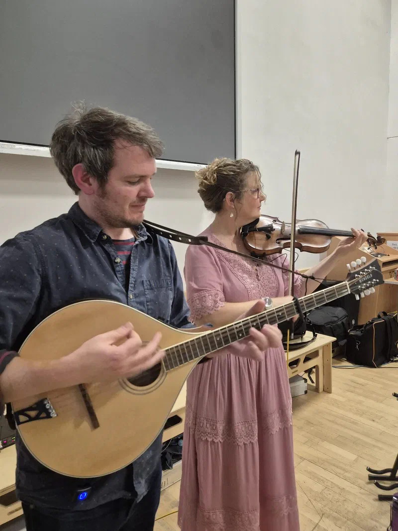 Tom on bouzouki and Sarah on fiddle playing side by side