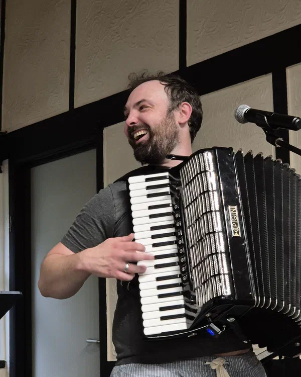 Dom playing accordion, laughing