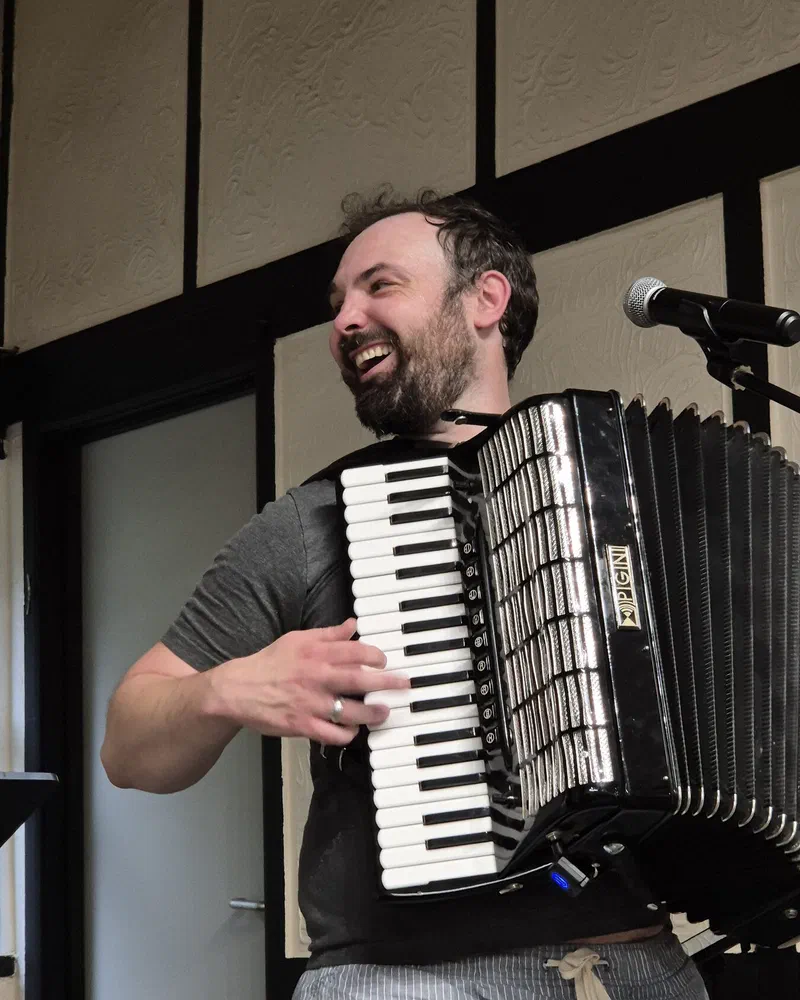 Dom playing accordion, laughing